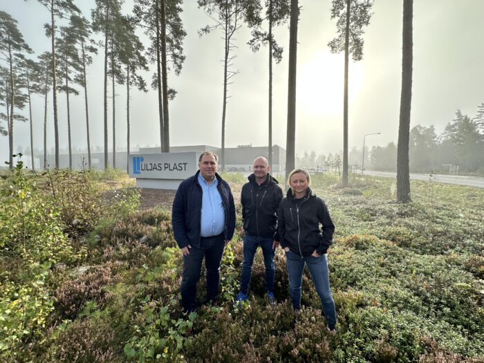 Two men and a woman standing in front of a Liljas Plast sign in nature